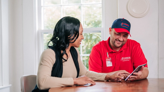 A Rainbow Restoration representative discusses property restoration services with a homeowner in Woodhaven, NY.