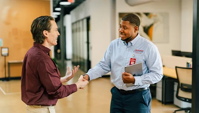 A Rainbow Restoration service professional shaking hands with a commercial customer.
