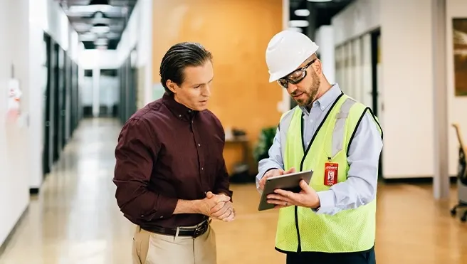 A Rainbow Restoration project manager discusses a property restoration project with a business owner in Dickinson, TX.
