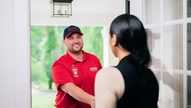 A Rainbow Restoration expert greets a Greensboro, NC, homeowner in need of emergency restoration services at their front door. 