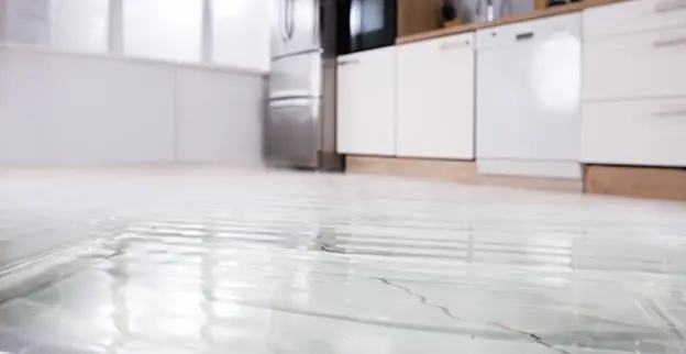 Water covers the floor of a kitchen after a water damage loss.