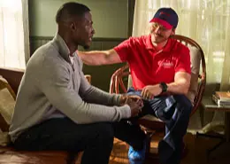 A Rainbow Restoration service professional seated with a customer and patting him on the back to reassure him during smoke and fire damage restoration work.