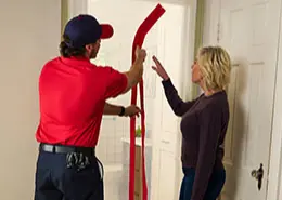 A Rainbow Restoration service professional standing with a customer next to a doorway in her home that's been outfitted with a dust barrier.