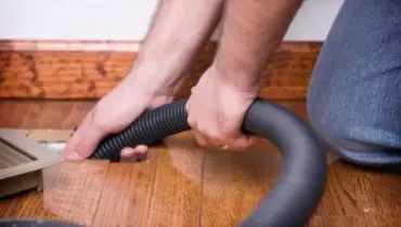 A Rainbow Restoration service professional cleaning an HVAC floor vent to remove dust and allergens and improve indoor air quality in a Jonesborough property.