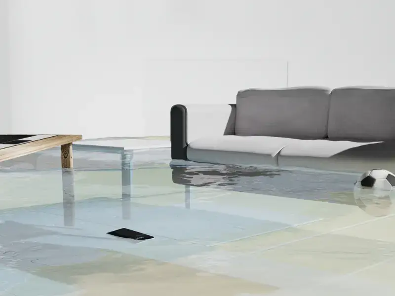 Floodwater covering the floor of a living room near a sofa illustrates how hidden water damage can spread through a home after a leak.