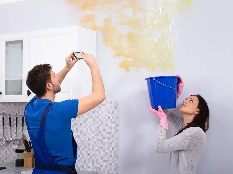 A homeowner and a restoration technician inspect ceiling and wall water damage, showing the early stages of professional water removal in a Johnson City home.
