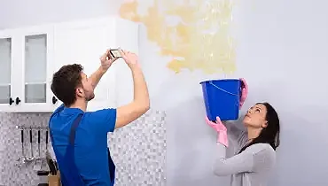 A homeowner and a restoration technician inspect ceiling and wall water damage, showing the early stages of professional water removal in a Johnson City home.
