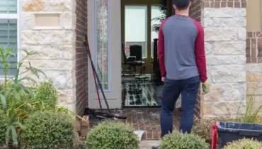 Man standing in front of an open doorway looking into flooded home