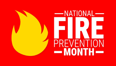 Red background with yellow flame and white lettering stating “National Fire Prevention Month”.