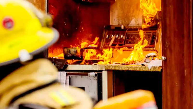 Firefighter looking at a burning stove in a kitchen.