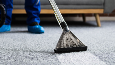 A professional cleaning a grey carpet.